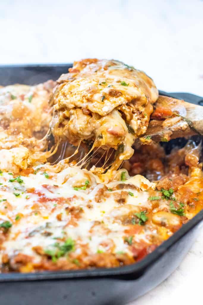 egy fakanál, amely egy sajtos darab lasagnát tart
