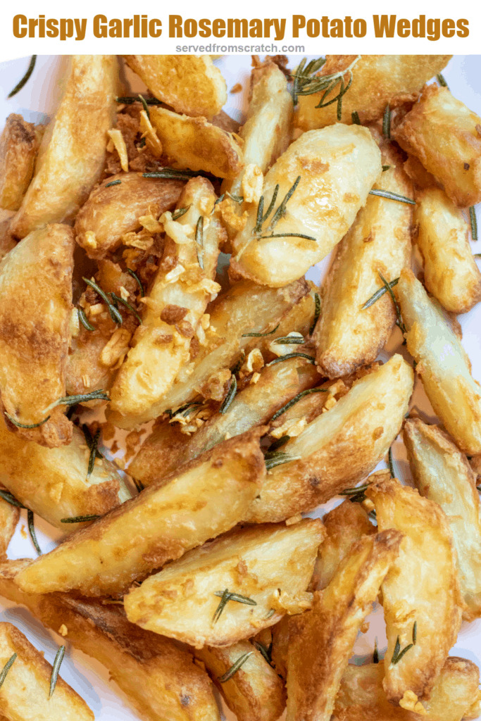 a plate of baked potato wedges topped with rosemary and garlic with Pinterest pin text.