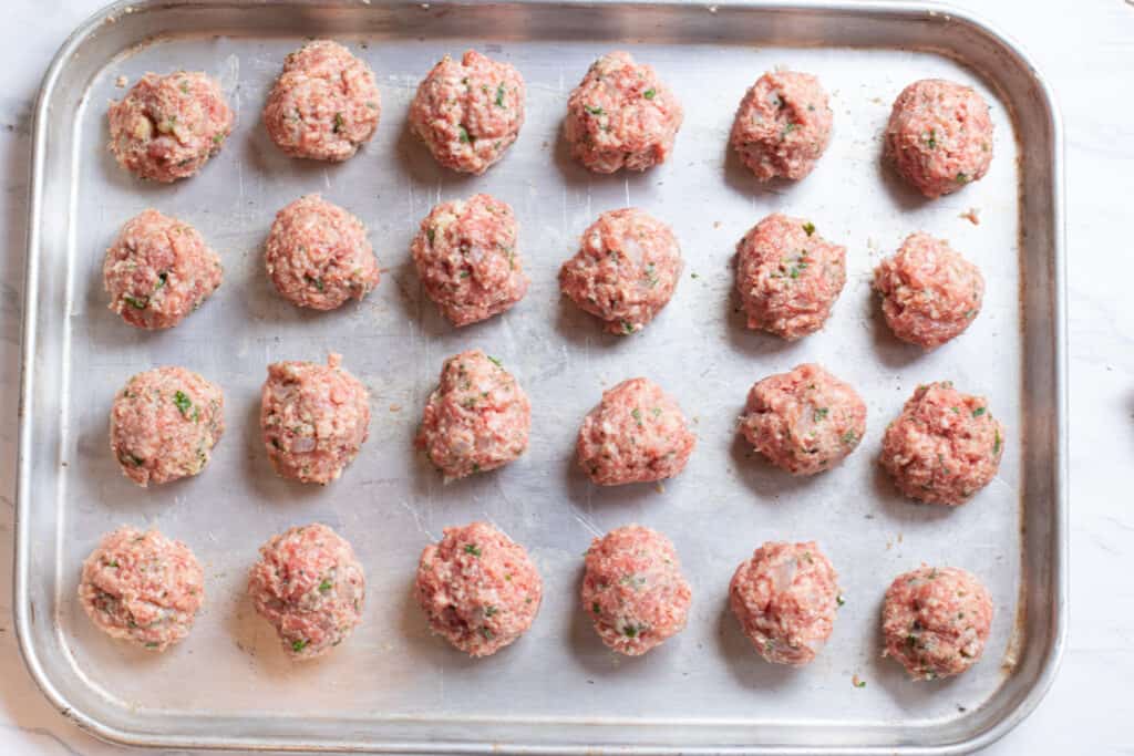 a baking sheet of a raw balls of meat