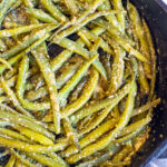 cooked green beans in a pan coated with mustard.