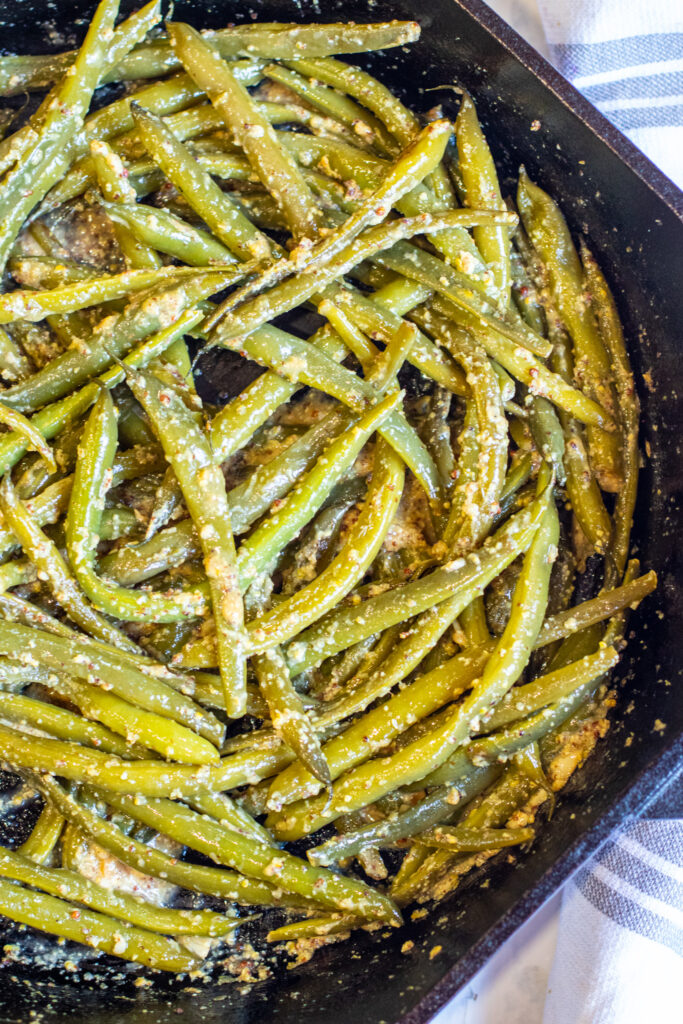 cooked green beans in a pan coated with mustard