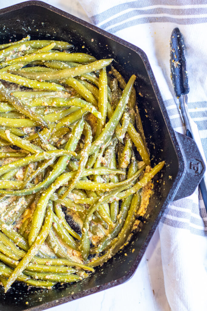 cooked green beans in a pan coated with mustard