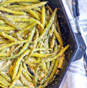 a cast iron with mustard coated green beans.