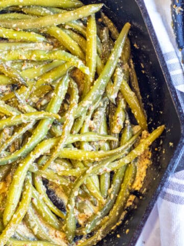 a cast iron with mustard coated green beans.