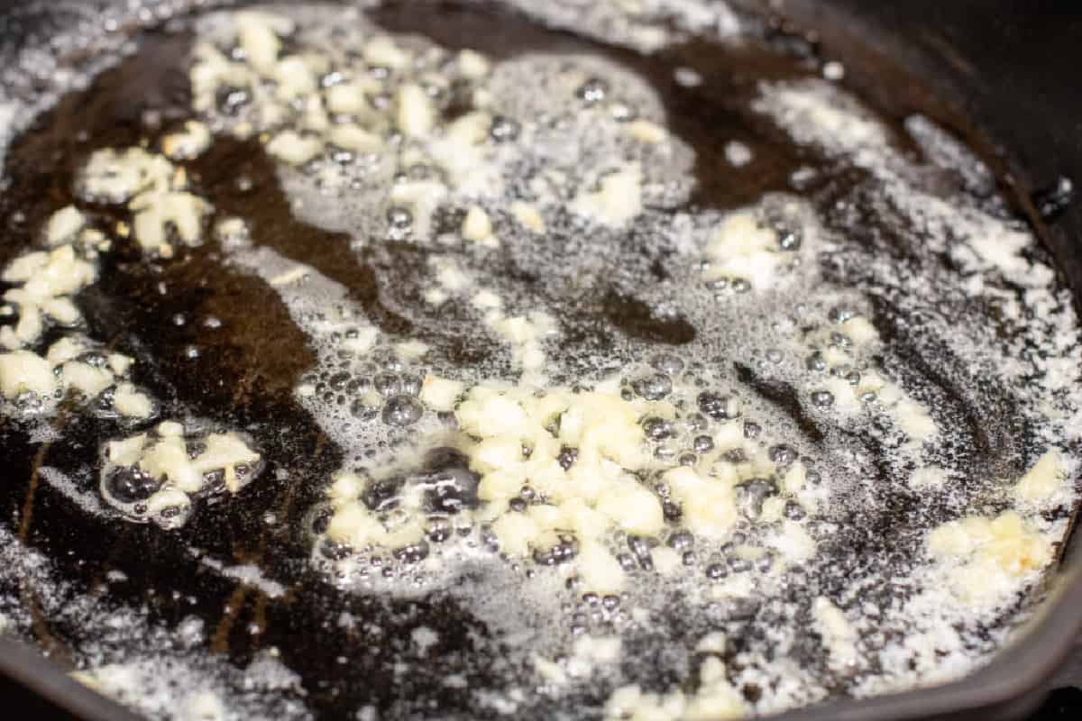 garlic cooking in butter in a sauté pan.