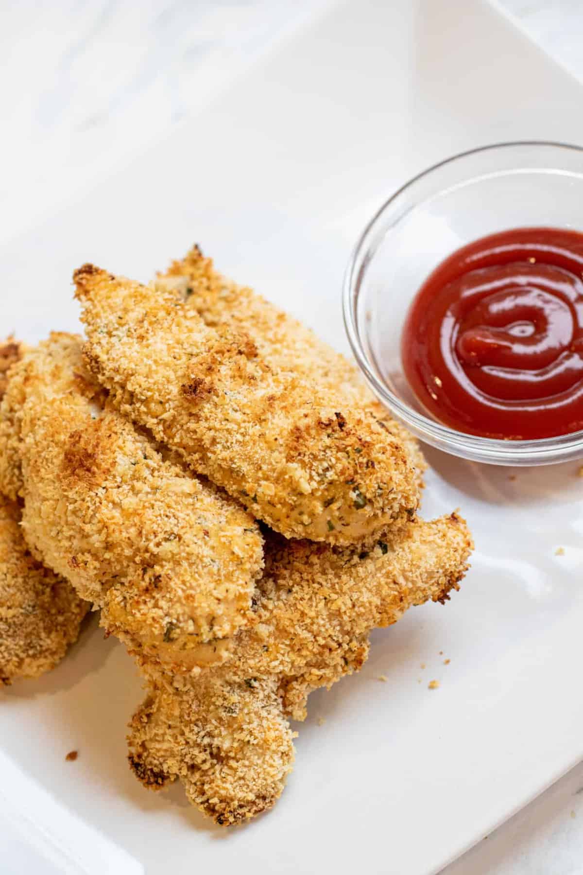 plate of baked chicken tenders and ketchup.