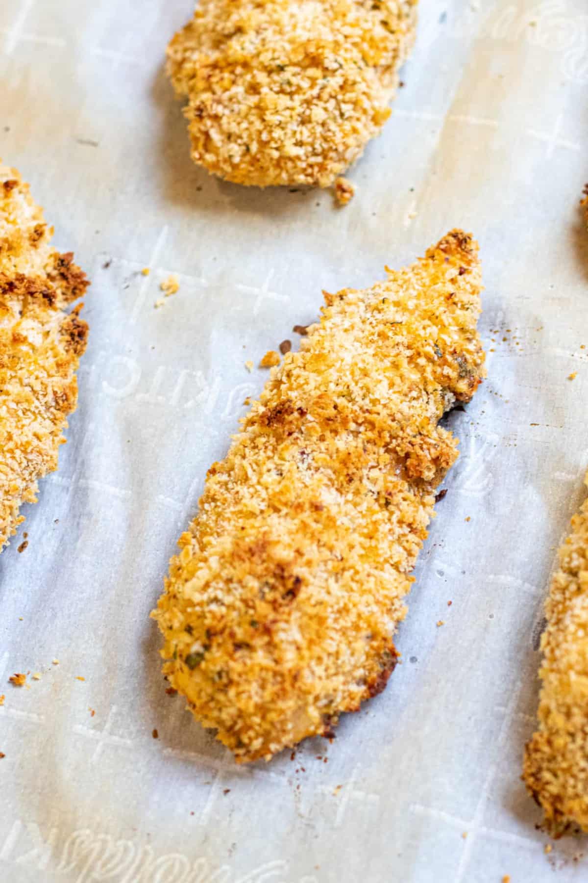 baked panko crusted chicken tender on parchment paper.