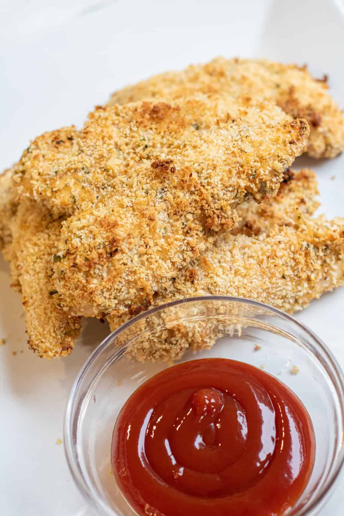 plate of baked chicken tenders and ketchup.
