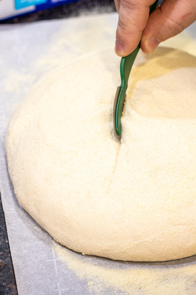 hand slicing top of bread dough