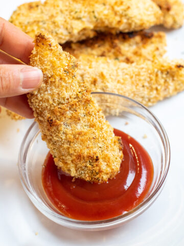 chicken tender being dipped in ketchup.