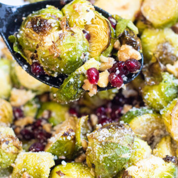 a spoon with roasted brussels, walnuts, and pomegranates.