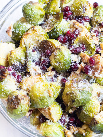 bowl of brussels sprouts and pomegranates topped with cheese.