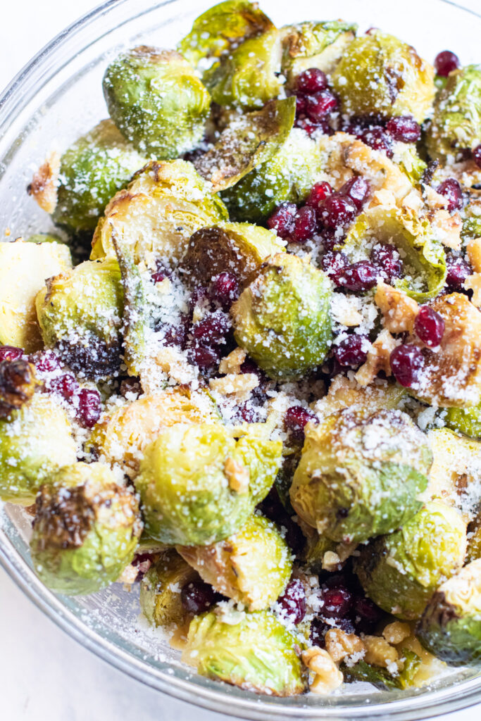 a bowl of brussels sprouts salad with pomegranates and cheese. 