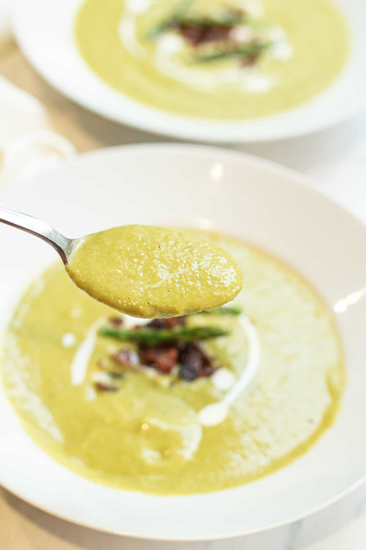 a spoonful of creamy green soup with Pinterest pin text.