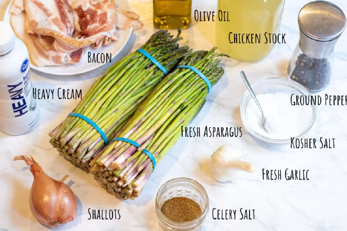 asparagus, bacon, stock, olive oil, pepper, salt, heavy cream, shallots, celery salt, garlic, and salt on a counter.