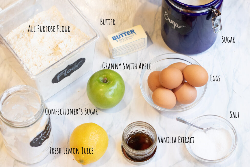 flour, apple, eggs, sugar, lemon, confectioner's sugar, vanilla extract, salt on counter