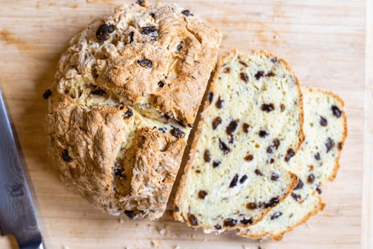 sliced soda bread with raisins on a cutting board with a knife.