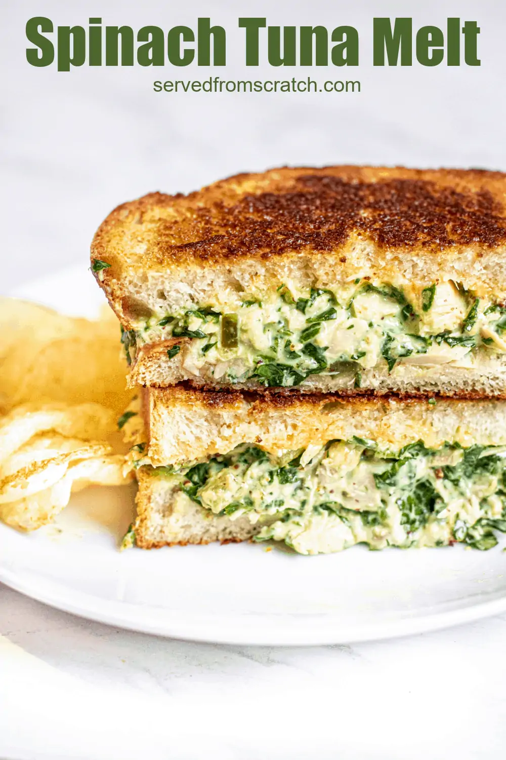 stacked tuna melt with spinach on a plate with chips.