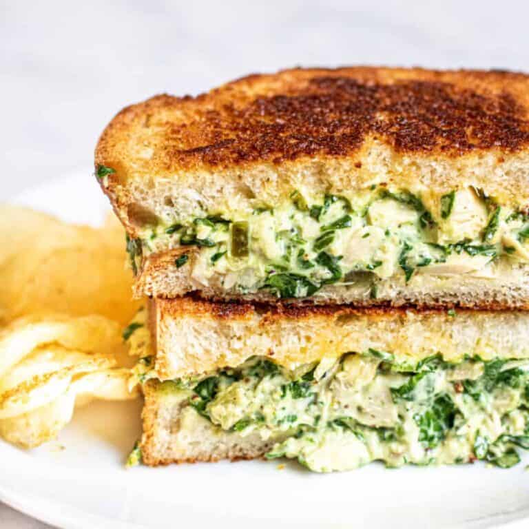 a tuna melt with spinach on a plate.