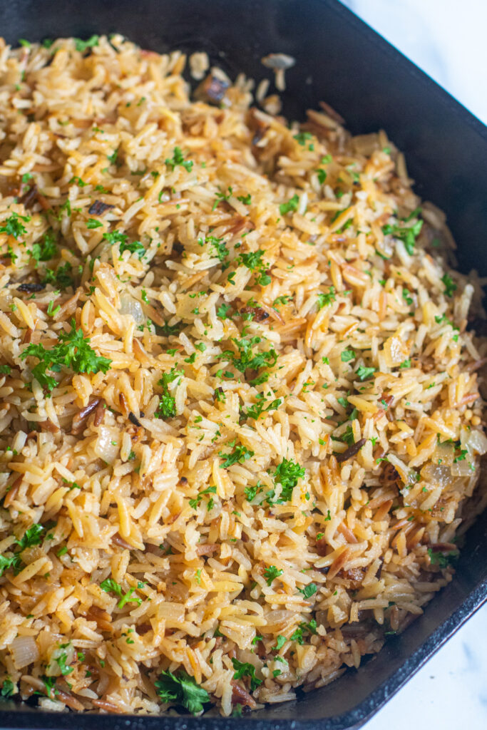 a cast iron with cooked rice pilaf and parsley