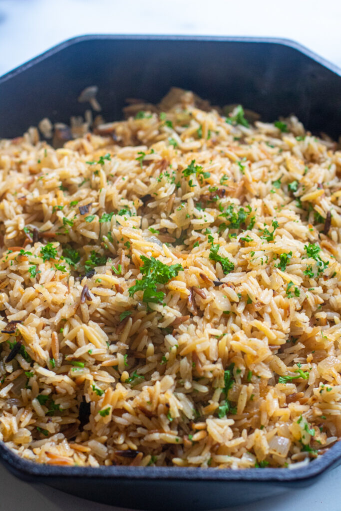 a cast iron with cooked rice pilaf and parsley