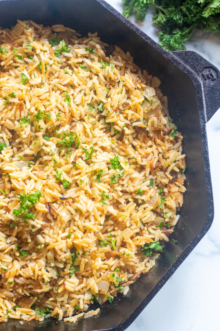 a cast iron with cooked rice pilaf and parsley.