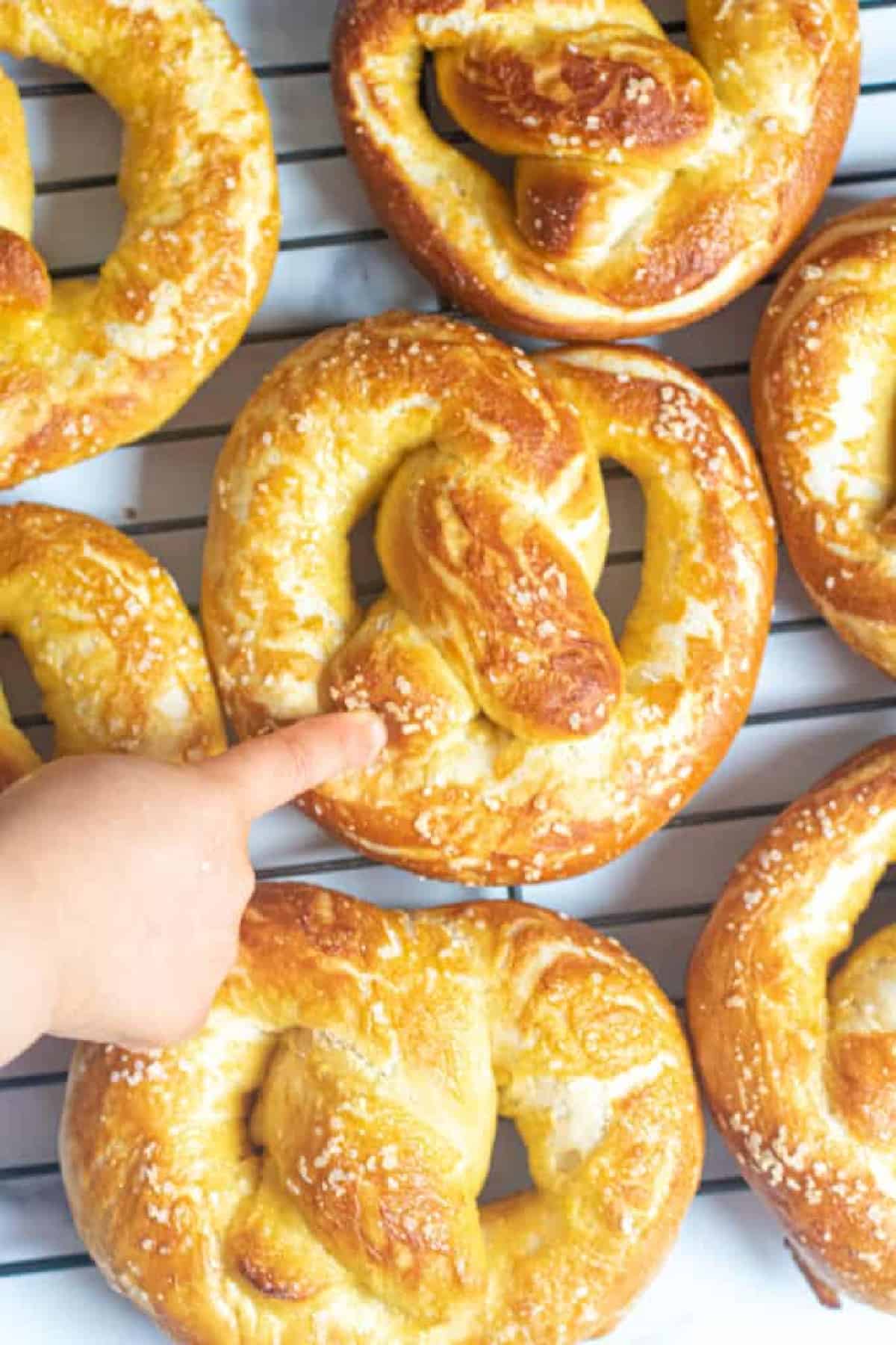 little hand pointing to a fresh baked pretzel.
