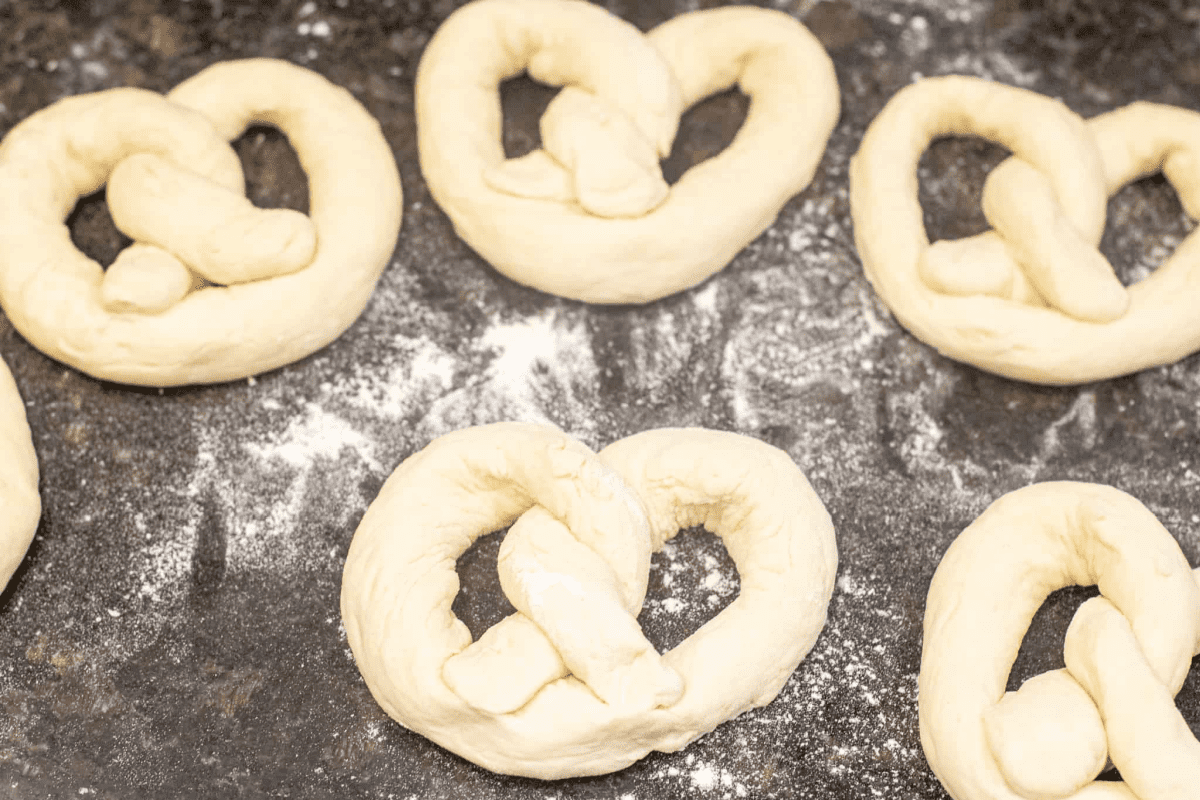 rolled unbaked raw soft pretzels on a counter.