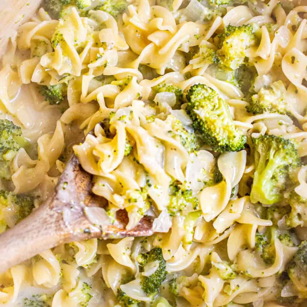 an overhead of a pot of egg noodles with creamy broccoli and a spoon.