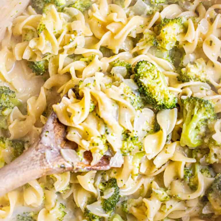 an overhead of a pot of egg noodles with creamy broccoli and a spoon.