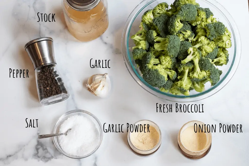 fresh broccoli, stock, pepper, salt, onion and garlic powder, and fresh garlic on a counter.