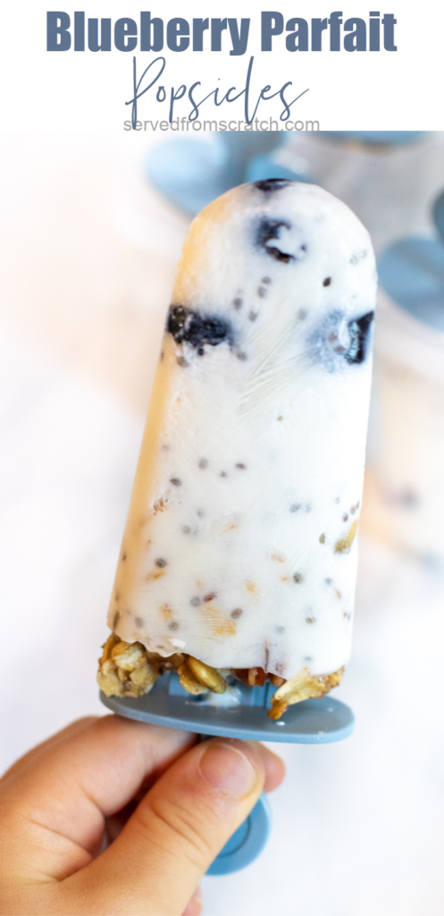 a hand holding a popsicle with blueberries and granola with Pinterest pin text.