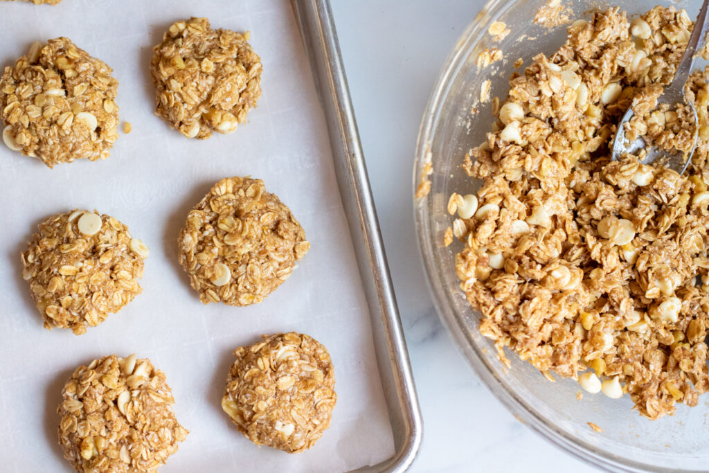 a baking sheet with raw cookies and a bowl of cookie dough.