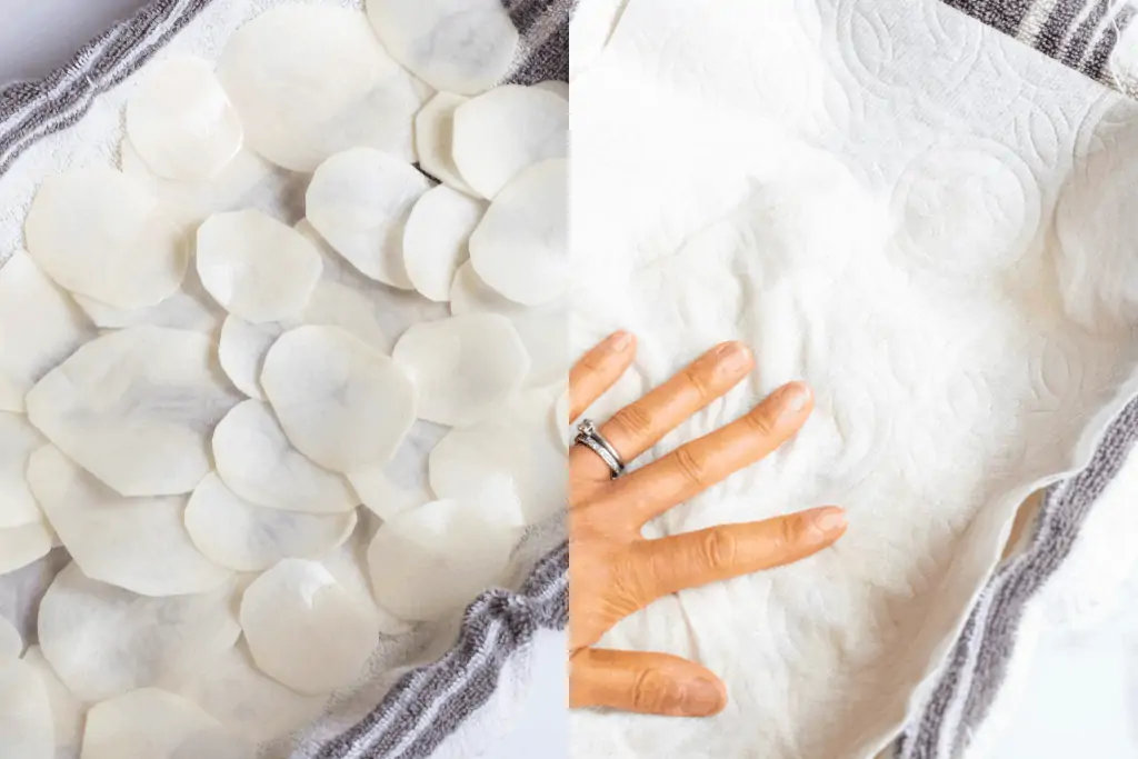 sliced potatoes on a towel and a hand holding a paper towel down.