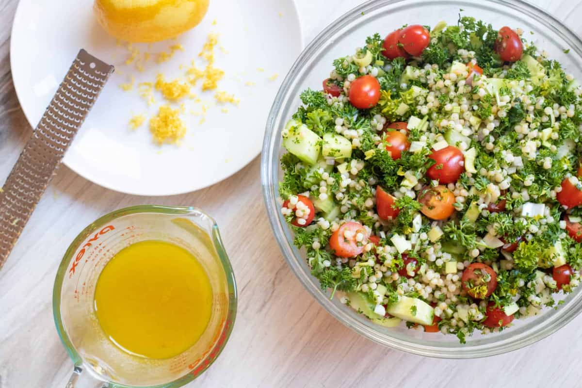 a bowl of cucumbers, parsley, couscous, cucumbers and a vinaigrette and zested lemon.