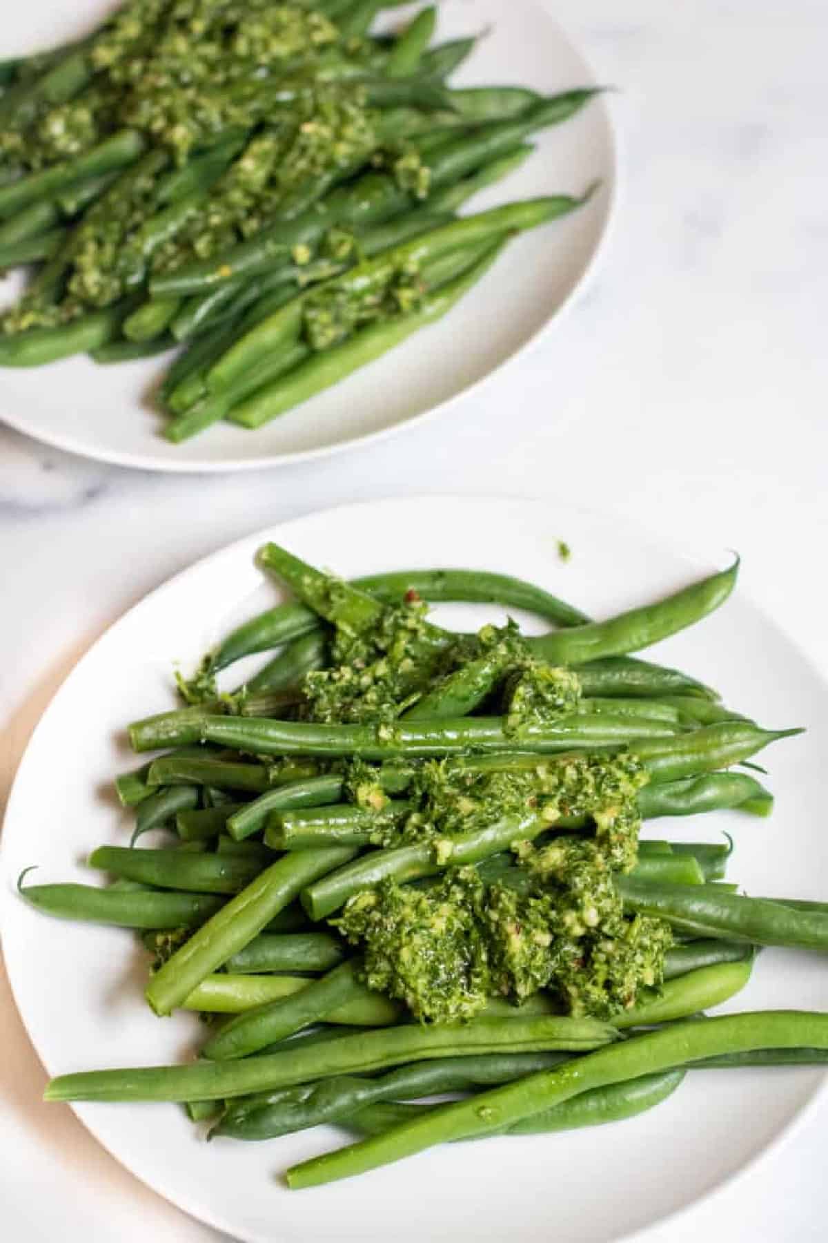 two plates with green beans and pesto.