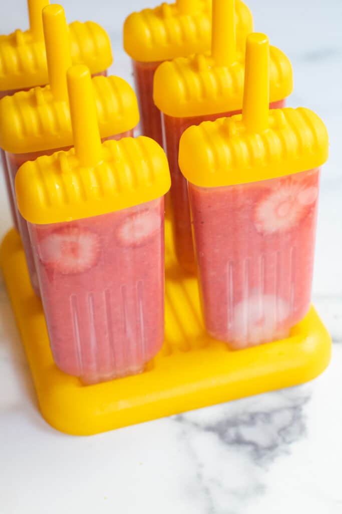 strawberry popsicles in a popsicle holder.
