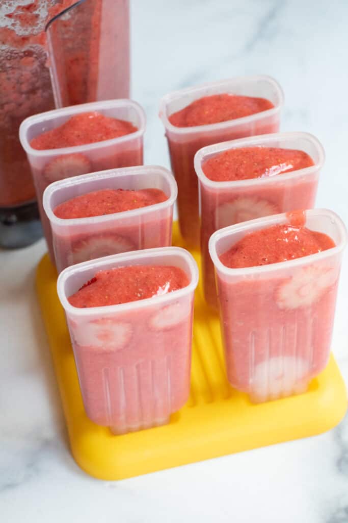 popsicle holders filled with strawberry mixture.