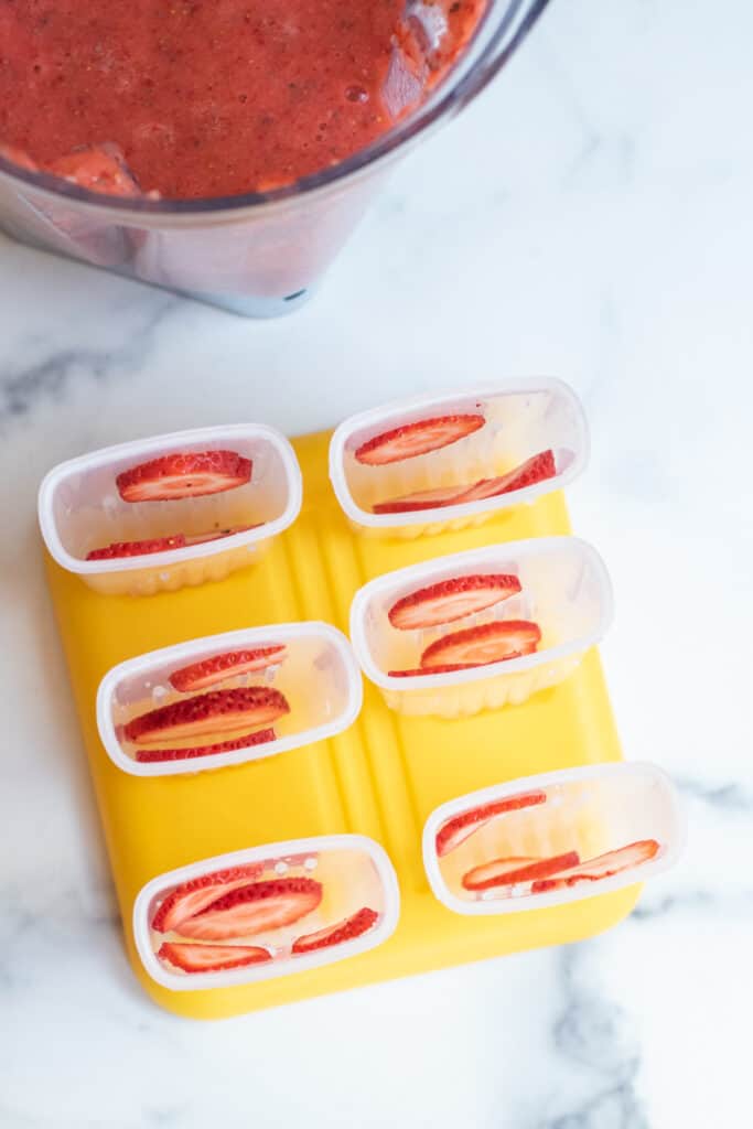 overhead of popsicle holder with sliced strawberries.