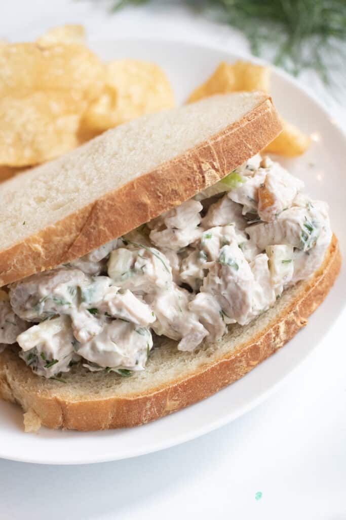 a stuffed sandwich with chicken salad on a plate with chips.