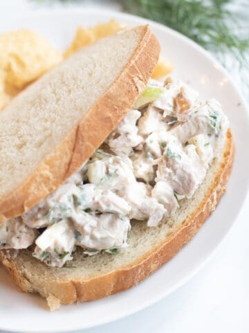 a stuffed sandwich with chicken salad on a plate with chips.
