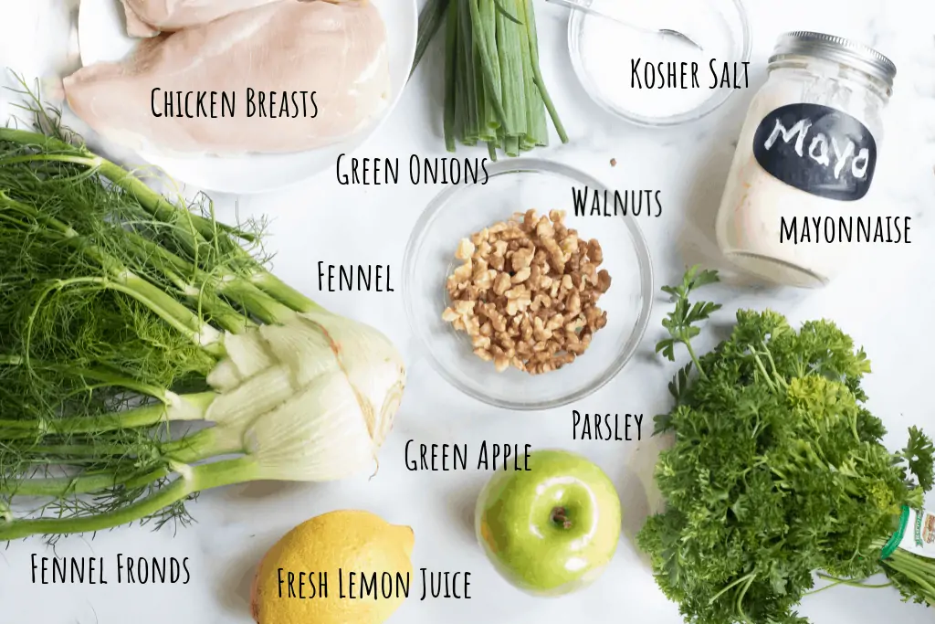fennel, chicken, green onions, parsley, mayo, apple, walnuts, lemons, apple on a counter.