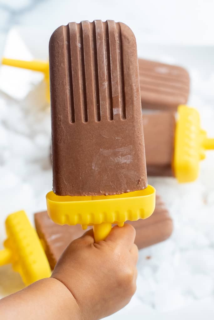 a kid's hand holding a fudgesicle.