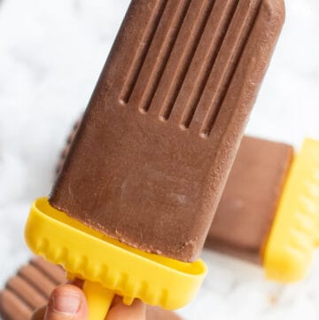 a kid's hand holding a fudgesicle.