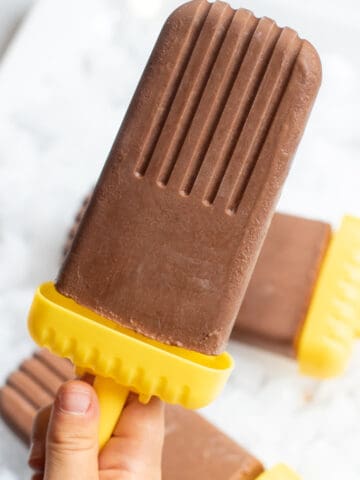 a kid's hand holding a fudgesicle.