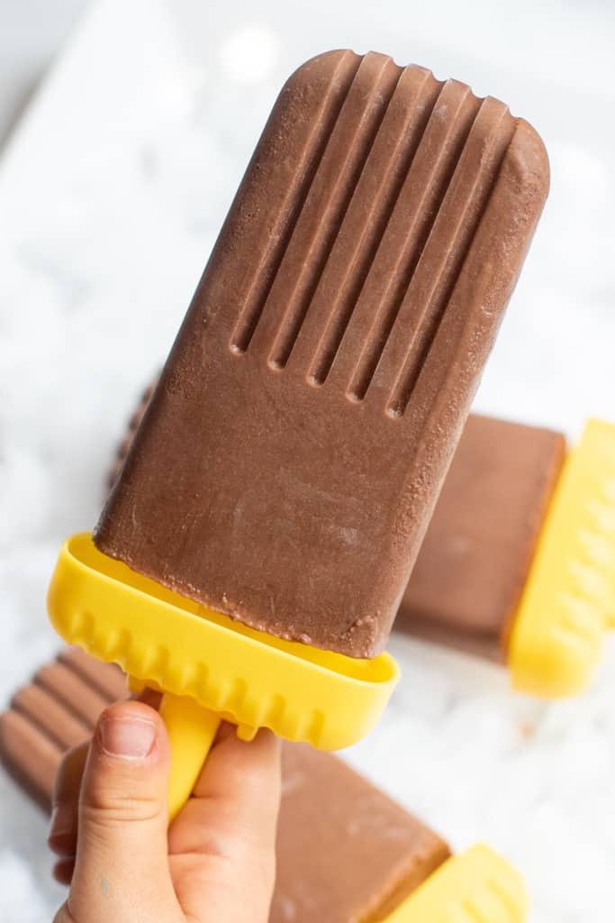 a kid's hand holding a fudgesicle.