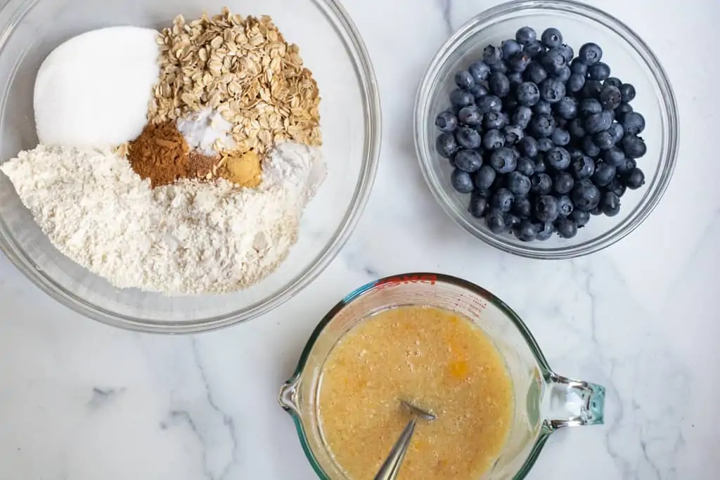 a bowl of oats, flour, sugar, spices, blueberries, and a pyrek of eggs and oil. 