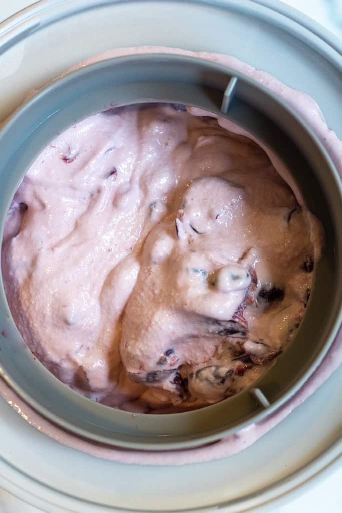 churned cherry ice cream in an ice cream maker churn.