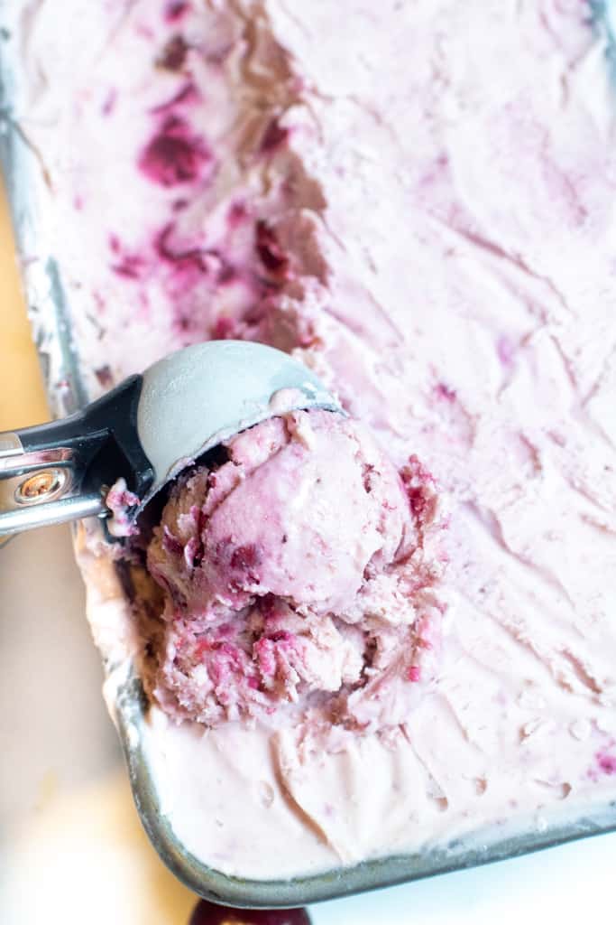 ice cream in a loaf pan scooped by an ice cream scoop.