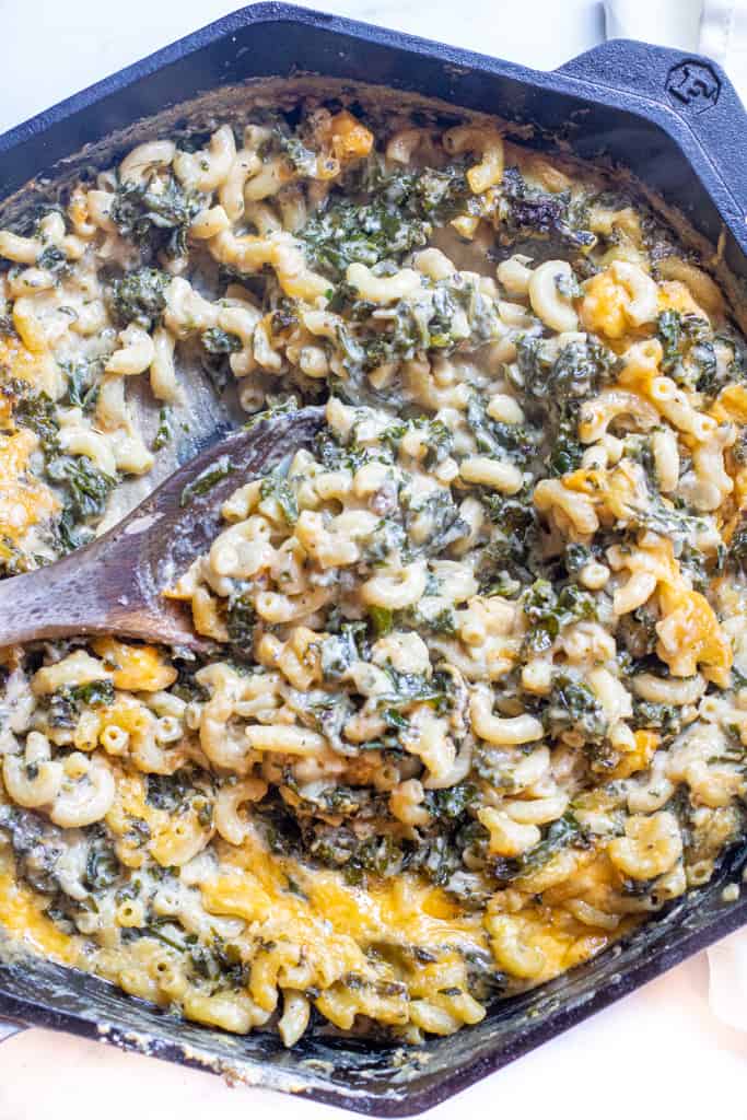 a spoon scooping some mac and cheese with kale.